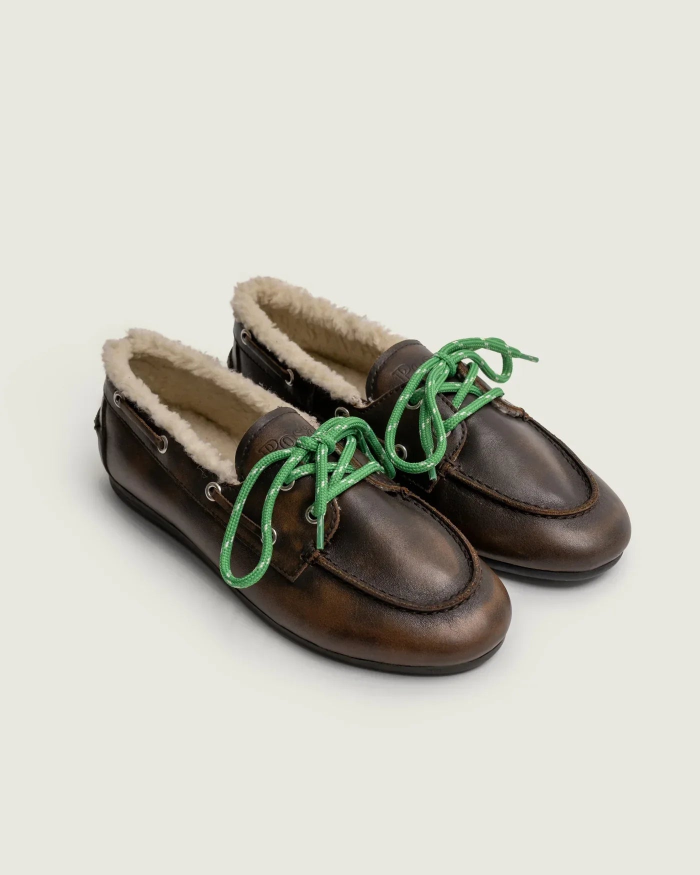 Braune Boat Loafer mit Shearling-Futter von Posa, eingefasst mit grünen Schnürsenkeln als farbigem Akzent.