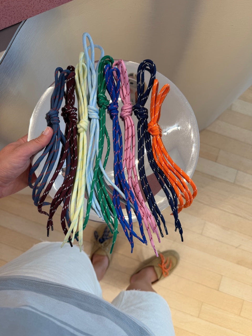 Hand hält ein Bündel verschiedenfarbiger Posa Schnürsenkel, nicht produktspezifisch.